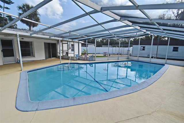 view of pool with a storage shed, a patio, and glass enclosure