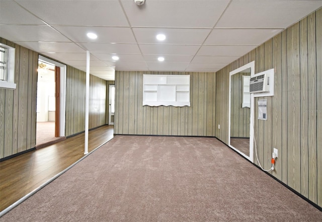 interior space with an AC wall unit, a paneled ceiling, and wood walls