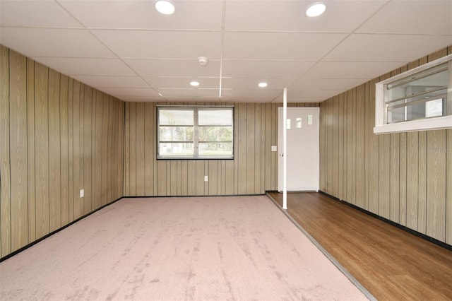 basement featuring a paneled ceiling and wooden walls