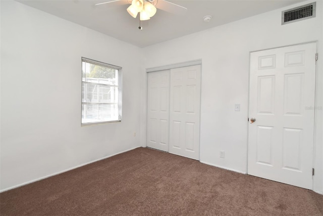 unfurnished bedroom featuring ceiling fan, dark carpet, and a closet