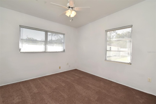 empty room with ceiling fan and dark colored carpet