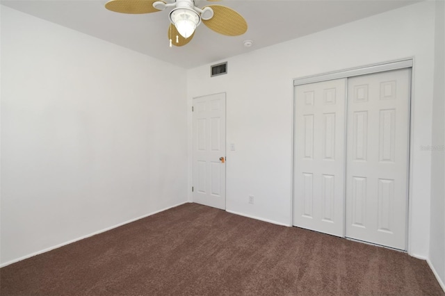 unfurnished bedroom featuring dark colored carpet, ceiling fan, and a closet