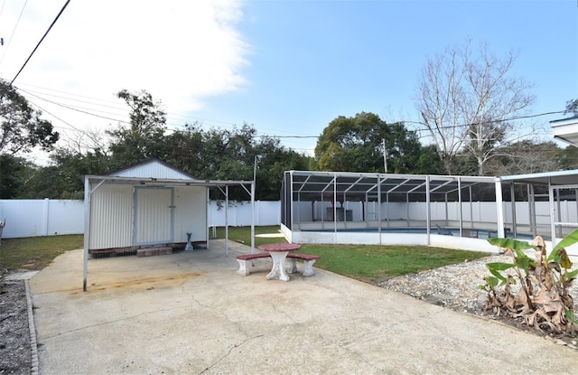 view of patio with a pool, glass enclosure, and a shed