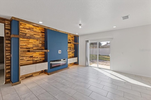 unfurnished living room with tile patterned flooring and a textured ceiling