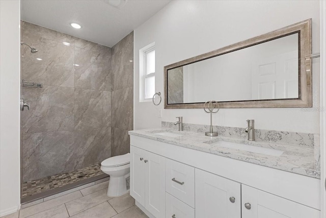 bathroom featuring vanity, a tile shower, and toilet