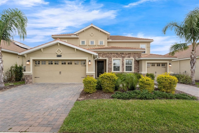 mediterranean / spanish house featuring decorative driveway, stucco siding, an attached garage, stone siding, and a front lawn