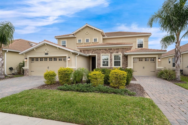 mediterranean / spanish-style home featuring a garage, stone siding, decorative driveway, and stucco siding