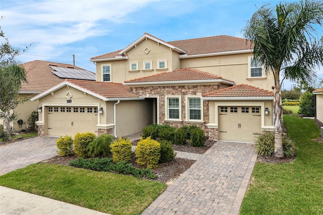 mediterranean / spanish-style home with a garage, stone siding, and decorative driveway