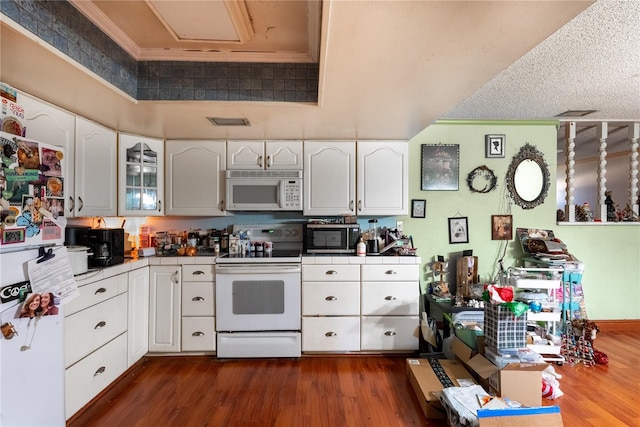 kitchen featuring ornamental molding, dark wood-type flooring, white cabinets, and white appliances