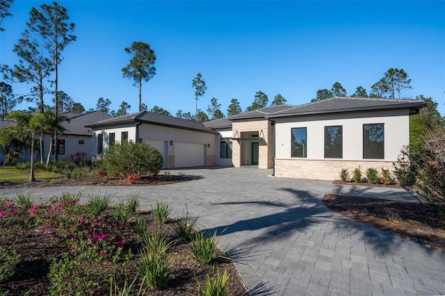 prairie-style house with decorative driveway, a garage, and stucco siding