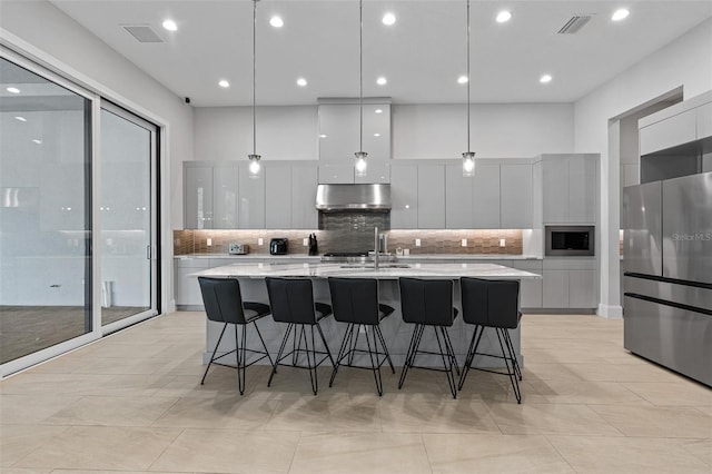 kitchen featuring visible vents, a large island, modern cabinets, under cabinet range hood, and stainless steel appliances