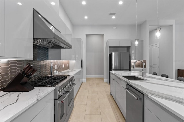 kitchen featuring visible vents, a sink, stainless steel appliances, wall chimney exhaust hood, and modern cabinets