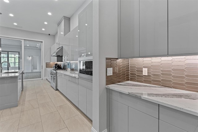 kitchen featuring modern cabinets, a sink, appliances with stainless steel finishes, decorative backsplash, and extractor fan