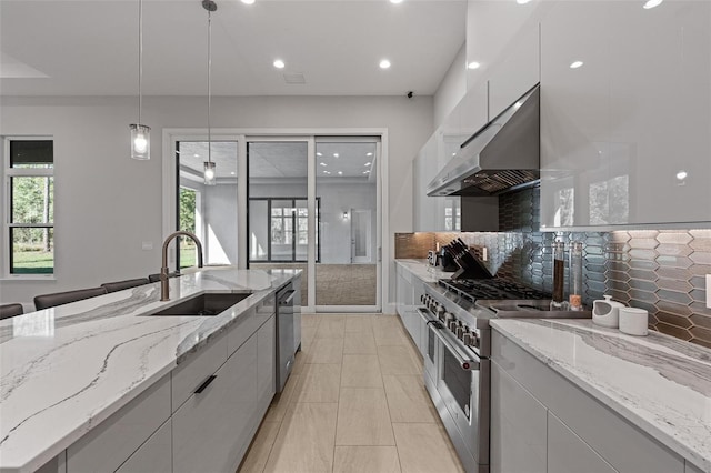 kitchen with under cabinet range hood, stainless steel appliances, modern cabinets, and a sink