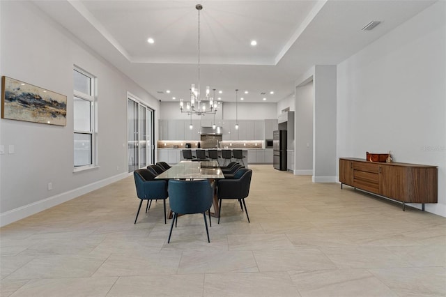 dining room featuring a tray ceiling, a notable chandelier, baseboards, and visible vents