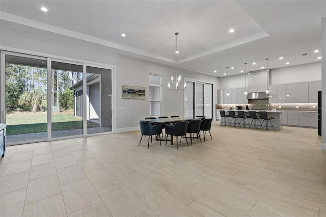 dining space with recessed lighting, a tray ceiling, baseboards, and a chandelier