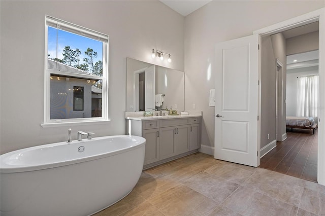 full bath featuring vanity, plenty of natural light, baseboards, and a freestanding bath