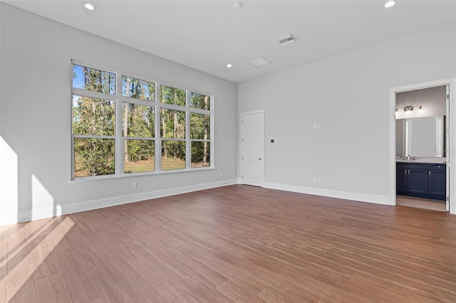 unfurnished living room with recessed lighting, baseboards, wood finished floors, and a sink