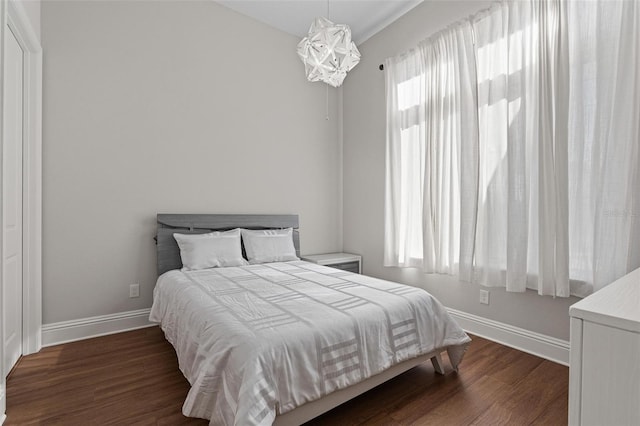 bedroom featuring multiple windows, baseboards, and wood finished floors