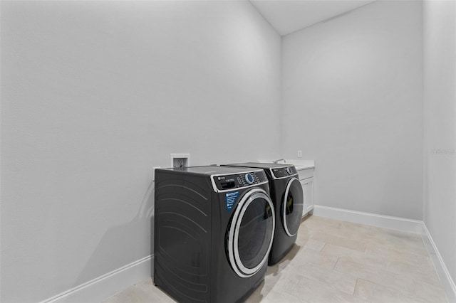 washroom featuring baseboards, cabinet space, and washing machine and dryer