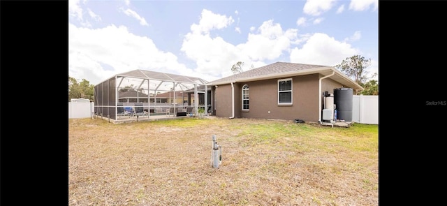 back of house featuring a lanai and a yard