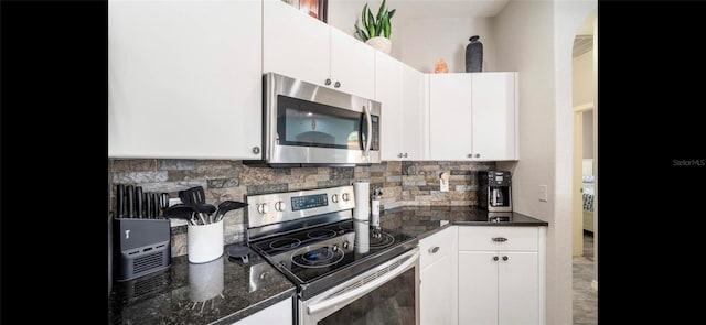 kitchen featuring decorative backsplash, appliances with stainless steel finishes, white cabinets, and dark stone counters