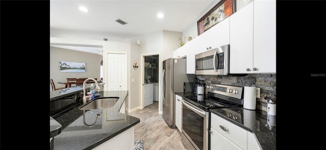 kitchen with tasteful backsplash, sink, white cabinets, dark stone counters, and stainless steel appliances