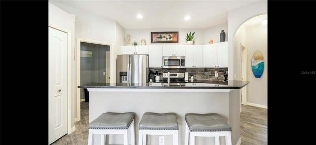 kitchen featuring white cabinetry, a kitchen island with sink, stainless steel appliances, and a kitchen breakfast bar