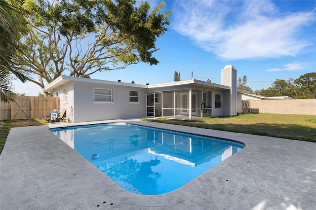 view of swimming pool featuring a patio, a sunroom, and a lawn