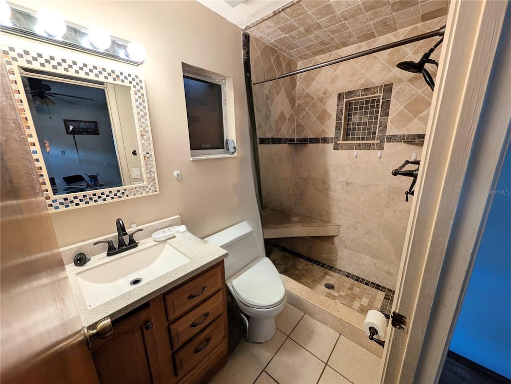 bathroom with vanity, a tile shower, tile patterned floors, and toilet