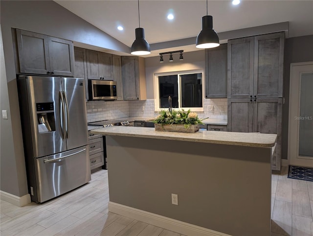 kitchen featuring hanging light fixtures, backsplash, appliances with stainless steel finishes, vaulted ceiling, and a kitchen island