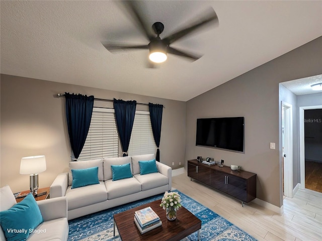 living area featuring baseboards, ceiling fan, vaulted ceiling, a textured ceiling, and light wood-style floors