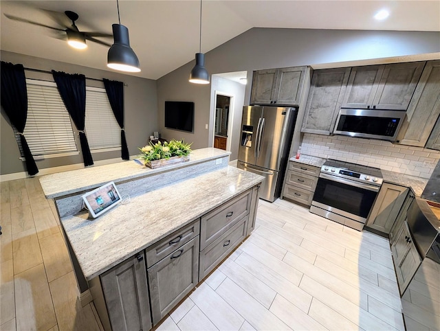 kitchen with stainless steel appliances, light stone counters, and hanging light fixtures