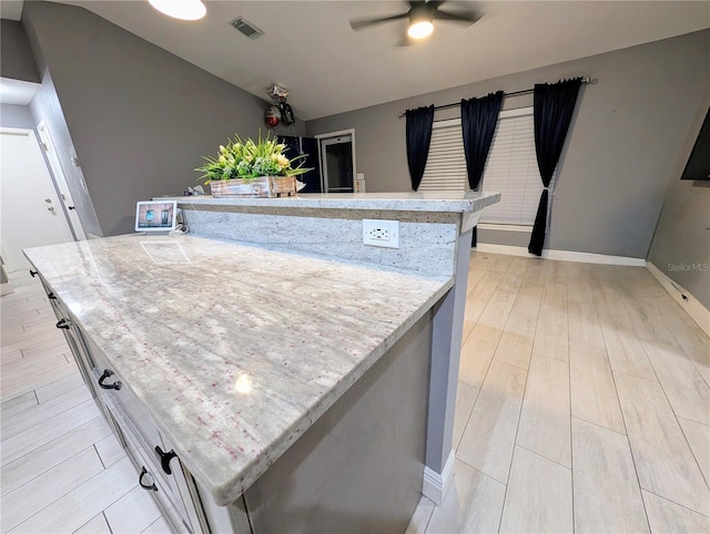 kitchen featuring a ceiling fan, light wood-type flooring, visible vents, and a kitchen island