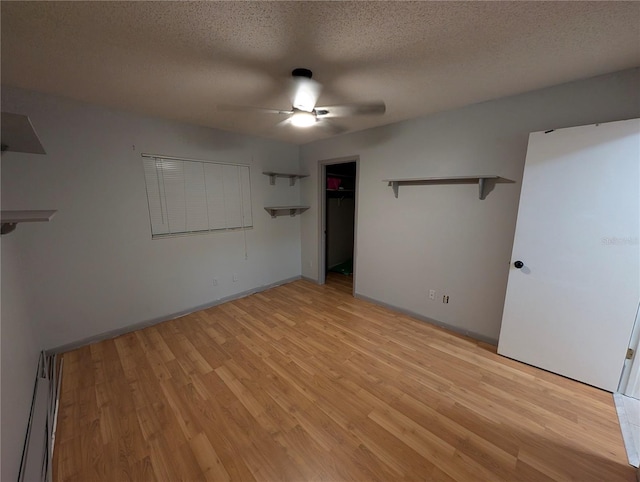 unfurnished bedroom with light wood finished floors, baseboards, a ceiling fan, a textured ceiling, and a baseboard heating unit