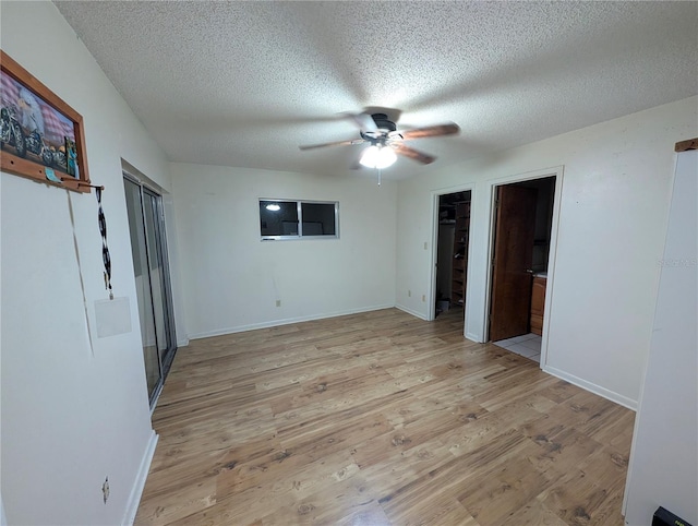 unfurnished bedroom featuring light wood finished floors, a ceiling fan, baseboards, and a textured ceiling