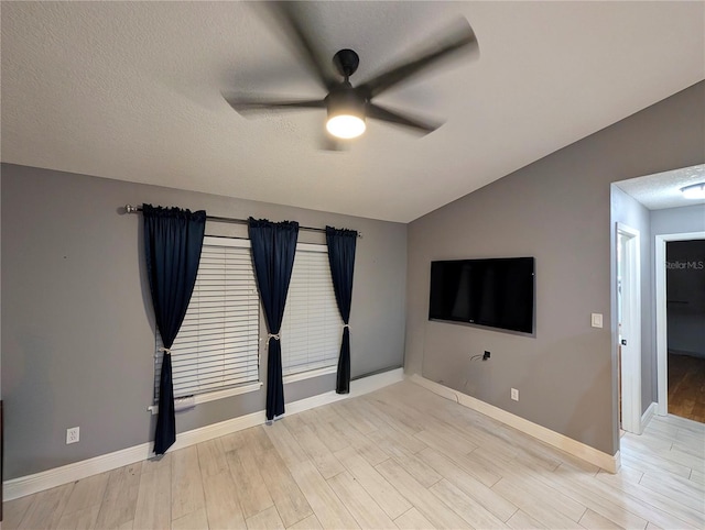 unfurnished living room with baseboards, lofted ceiling, ceiling fan, a textured ceiling, and light wood-type flooring