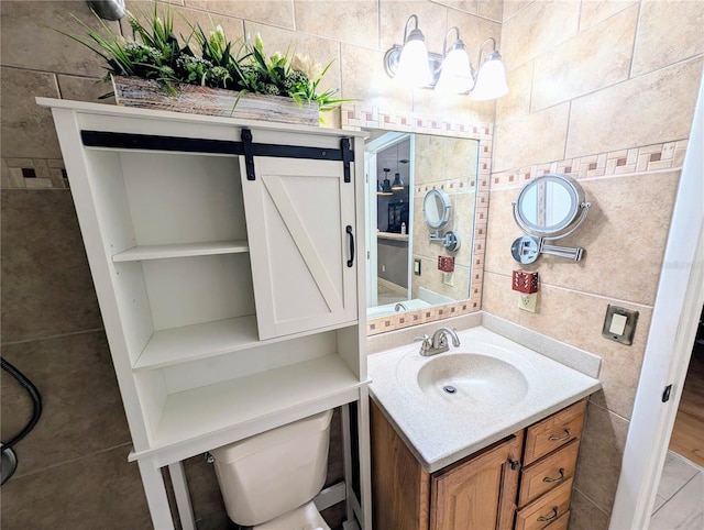 bathroom featuring toilet, vanity, and tile walls