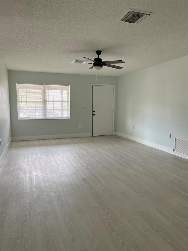 spare room featuring a textured ceiling, light hardwood / wood-style flooring, and ceiling fan
