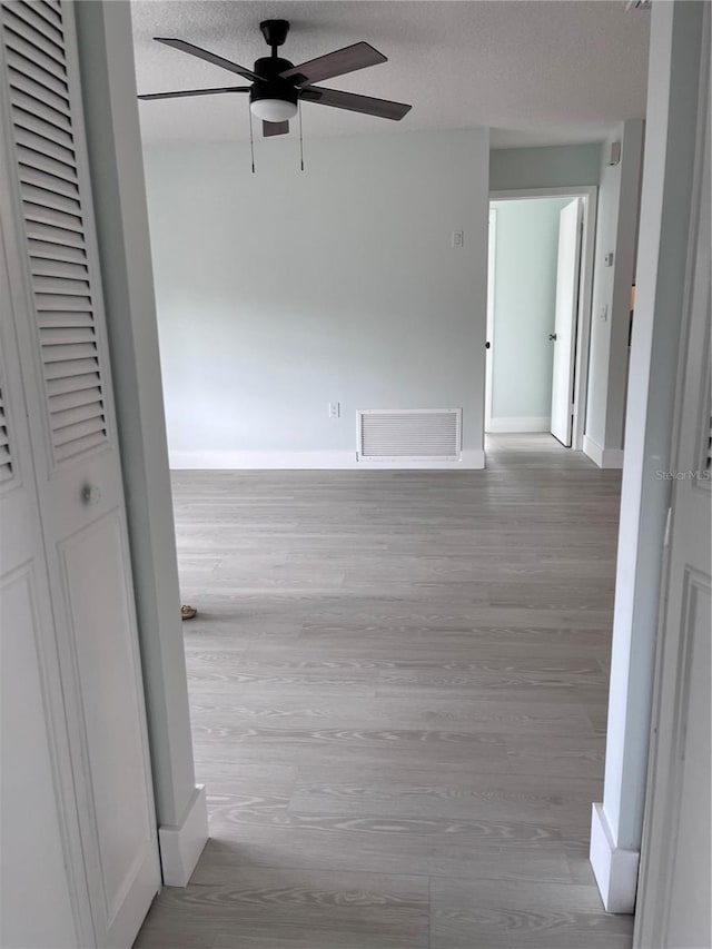 hallway with light hardwood / wood-style floors and a textured ceiling