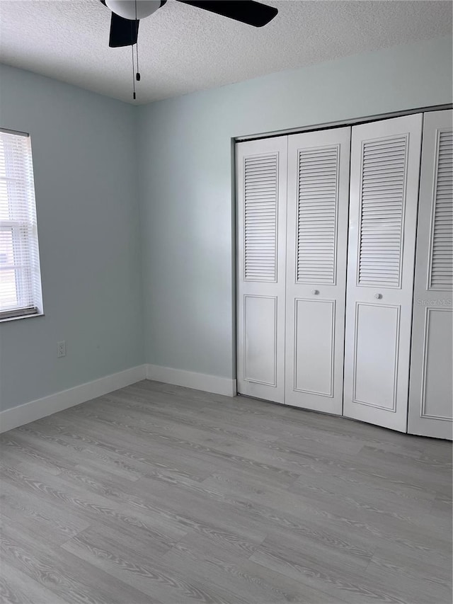 unfurnished bedroom featuring ceiling fan, light hardwood / wood-style floors, a closet, and a textured ceiling
