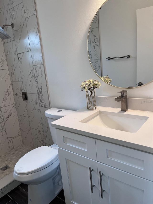 bathroom featuring vanity, toilet, and a tile shower