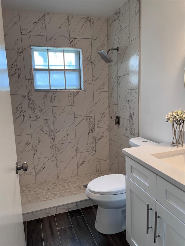 bathroom with vanity, toilet, and tiled shower