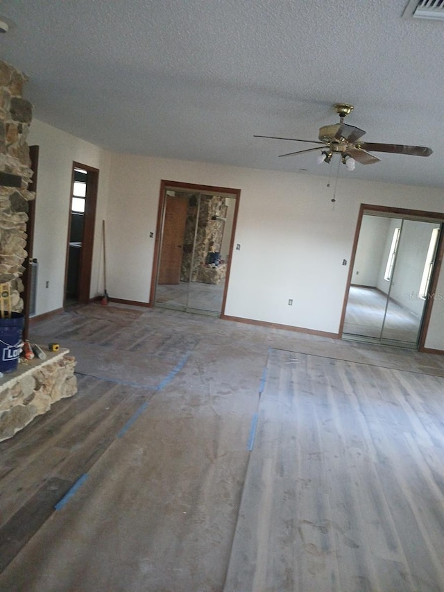 unfurnished living room featuring ceiling fan, wood-type flooring, and a textured ceiling