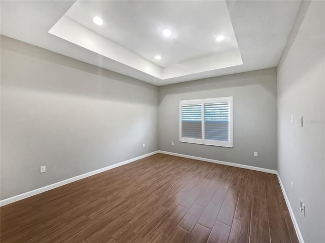 unfurnished room with dark wood-type flooring and a tray ceiling