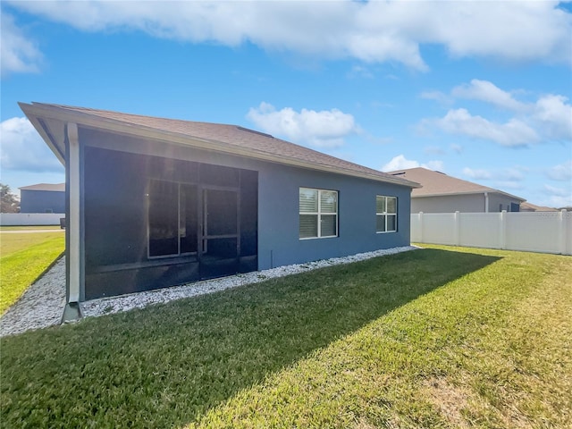 rear view of property featuring a lawn and a sunroom