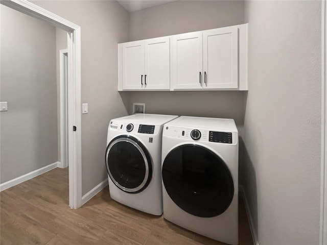 clothes washing area with cabinets, light hardwood / wood-style floors, and washer and dryer