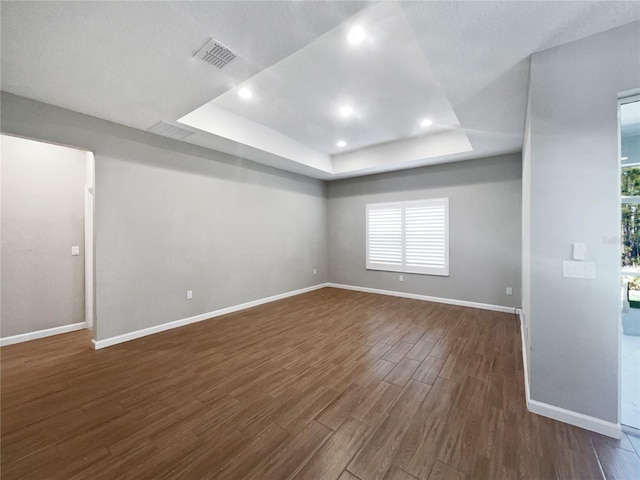 spare room featuring dark wood-type flooring and a raised ceiling