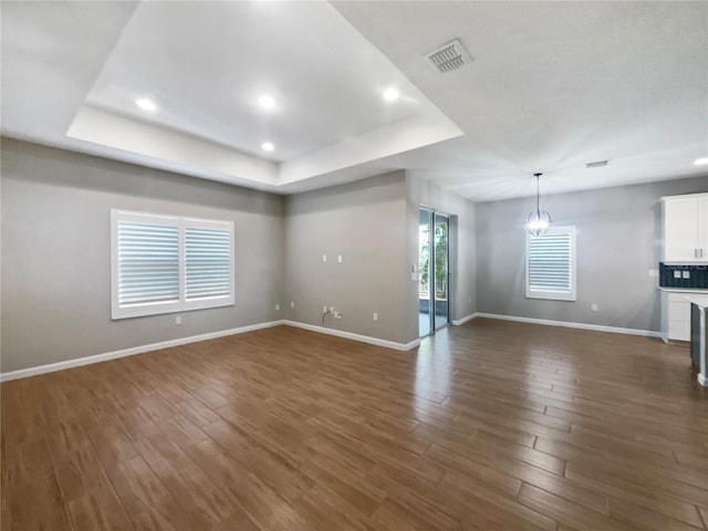 unfurnished living room with a raised ceiling and dark hardwood / wood-style floors