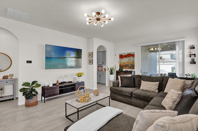 living room featuring an inviting chandelier, light hardwood / wood-style floors, and a textured ceiling